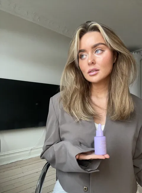 Creator presenting Guney & Stem hair oil in a grey blazer