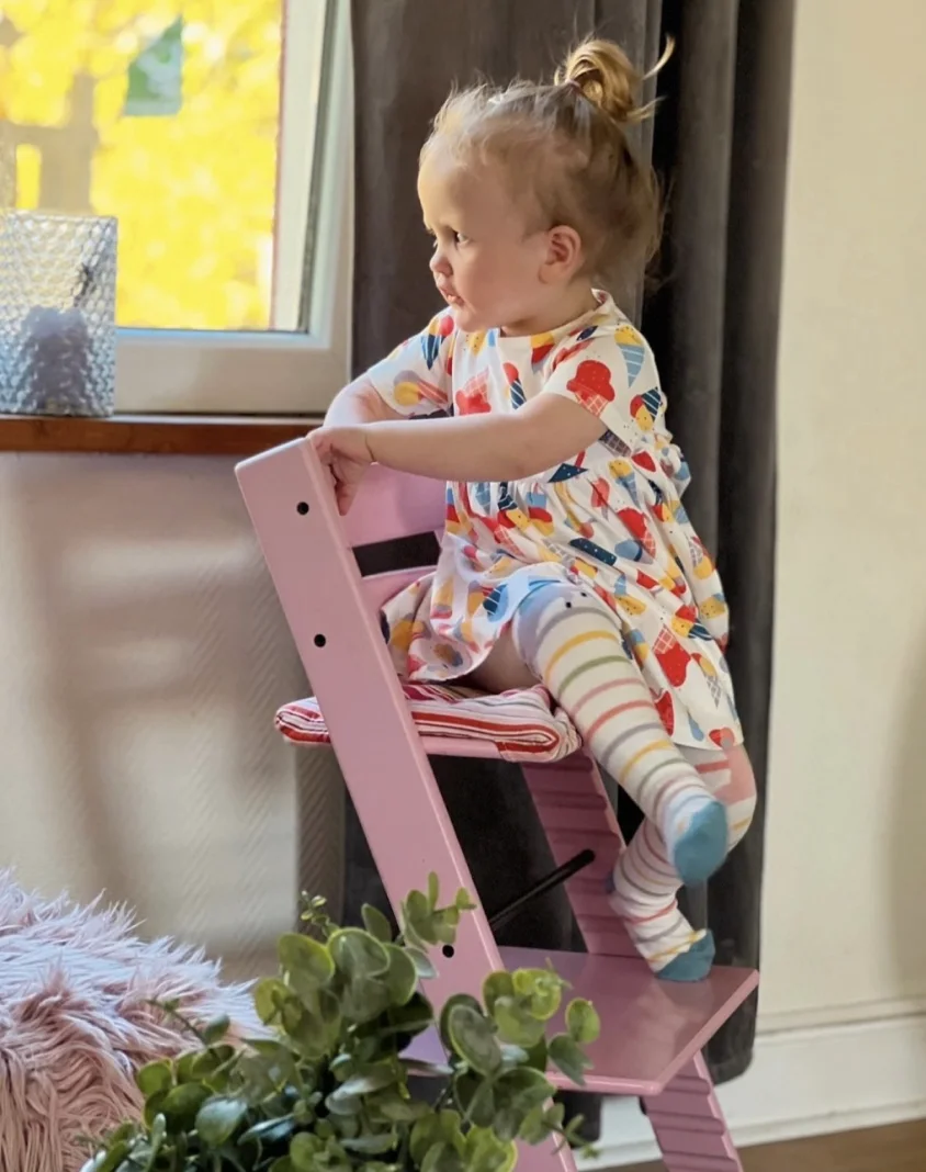 Child wearing patterned clothing on a pink chair
