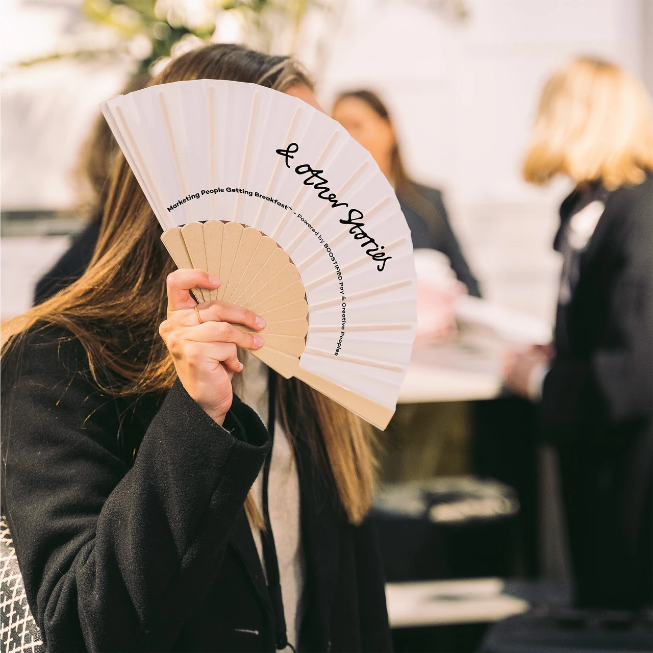 A guest holding a folding fan at & Other Stories.