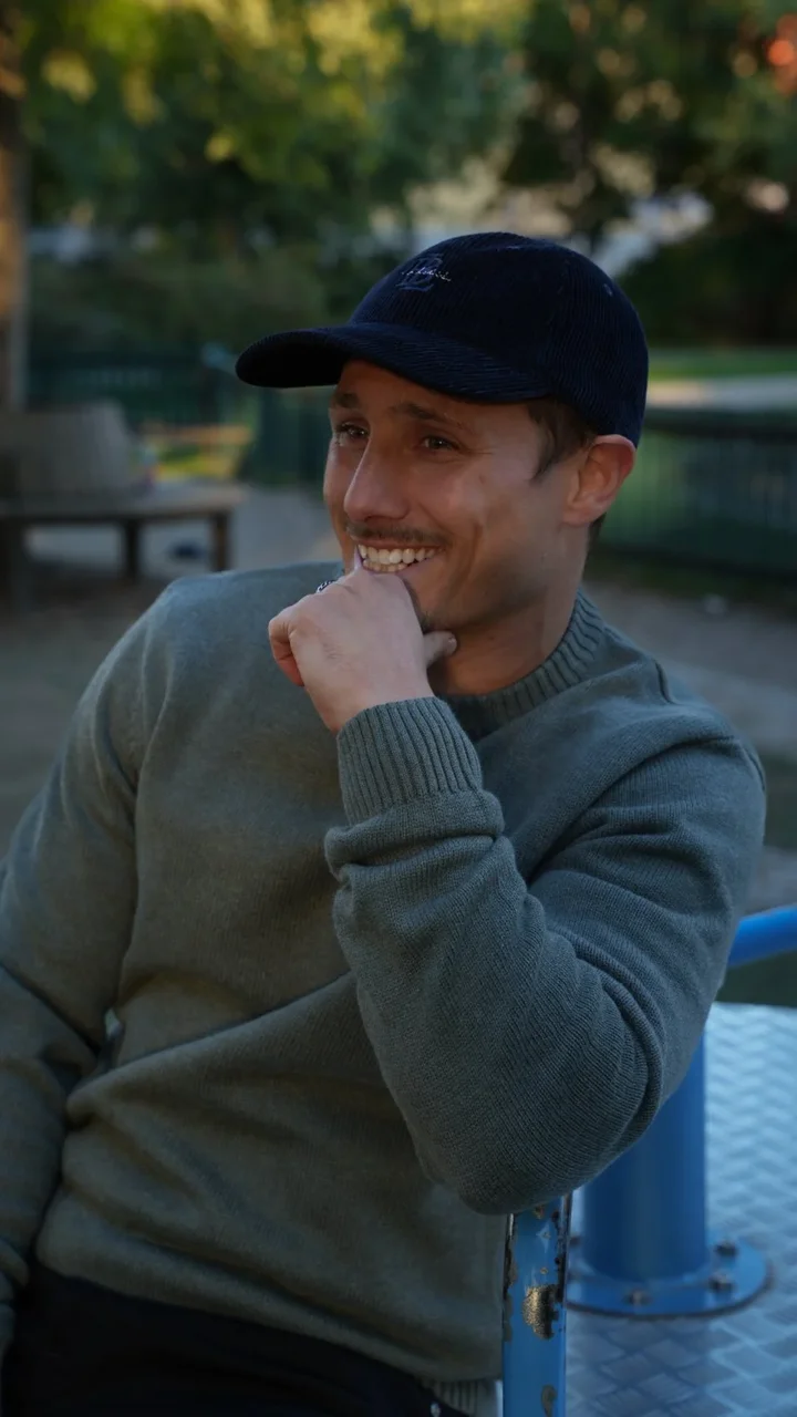 Creator wearing a grey sweater and a cap outdoors