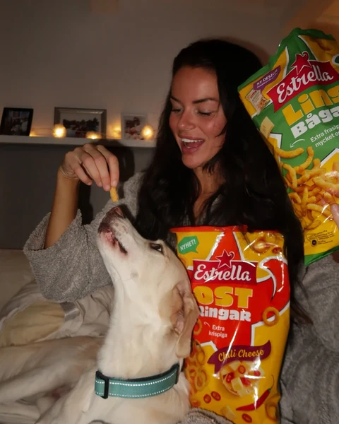 Creator holding Estrella snacks beside a dog