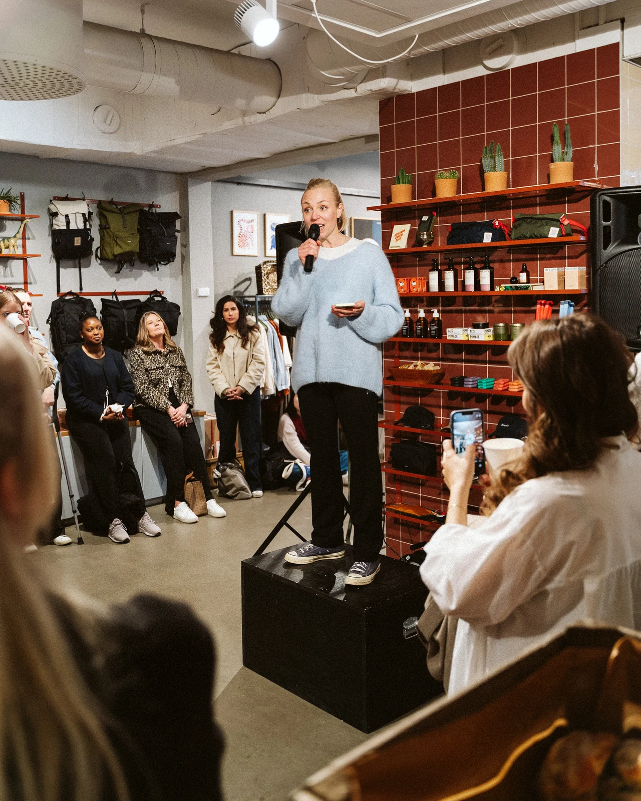 A speaker holding a microphone and notes at Grandpa Store.