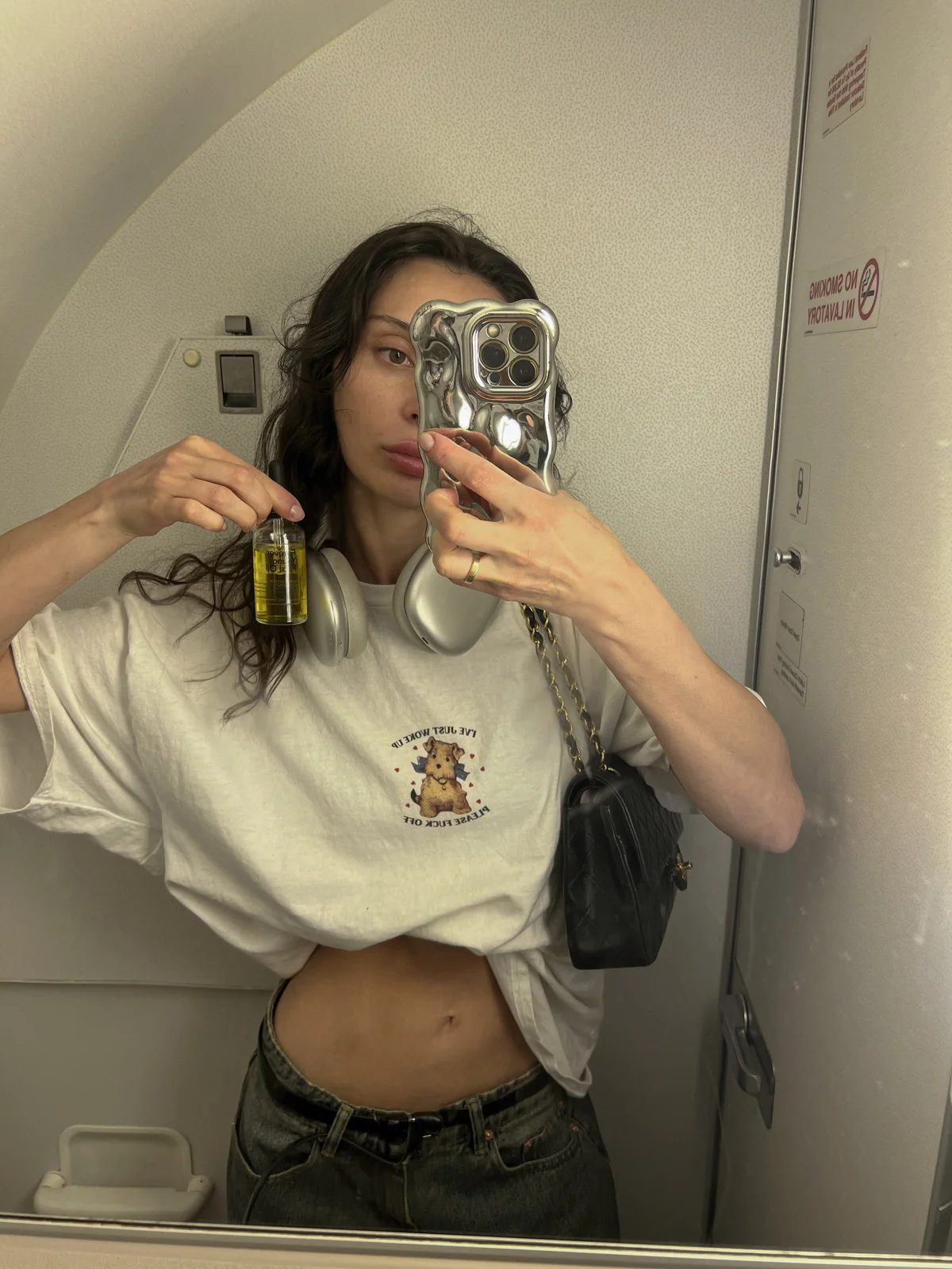 Creator holding face oil in a mirror selfie