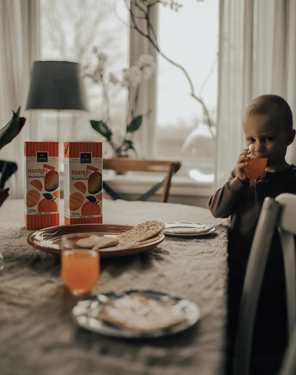Child enjoying a drink at a breakfast table with Kiviks mango drinks