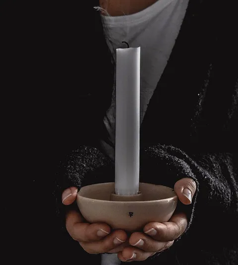 Hands holding a ceramic candleholder