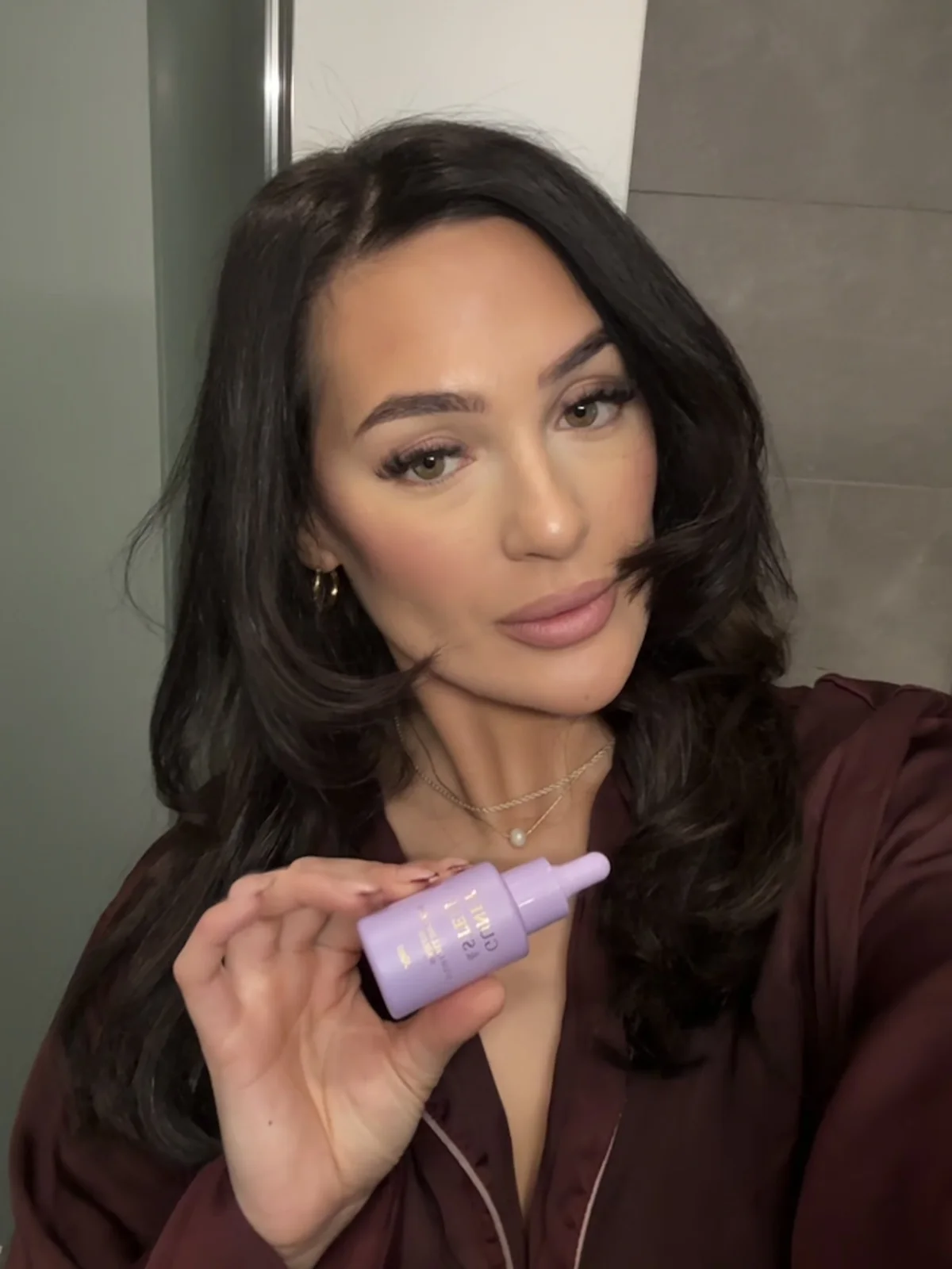 Creator holding Guney & Stem hair oil beside her hair