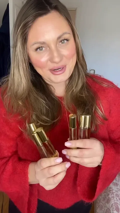 A creator in a red jumper holding Alyssa Ashley fragrance bottles