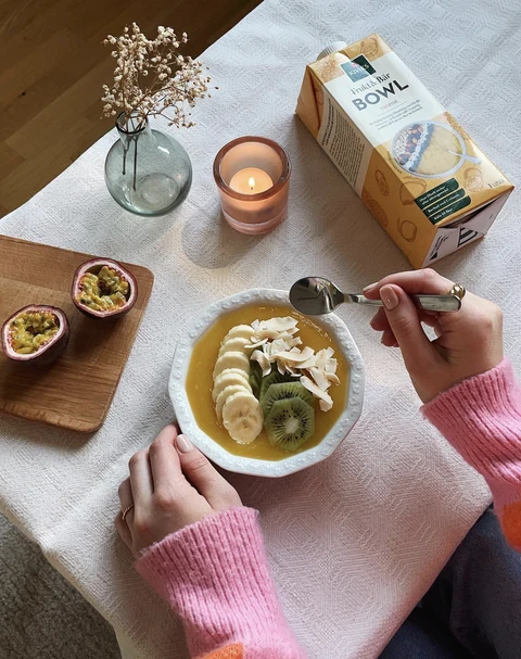 Fruit bowl topped with banana and kiwi beside a Kiviks Bowl carton