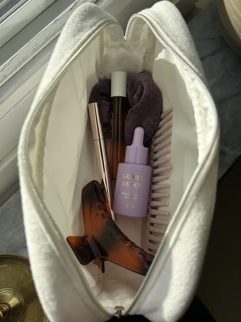 Guney & Stem hair oil in a toiletry bag with hair accessories