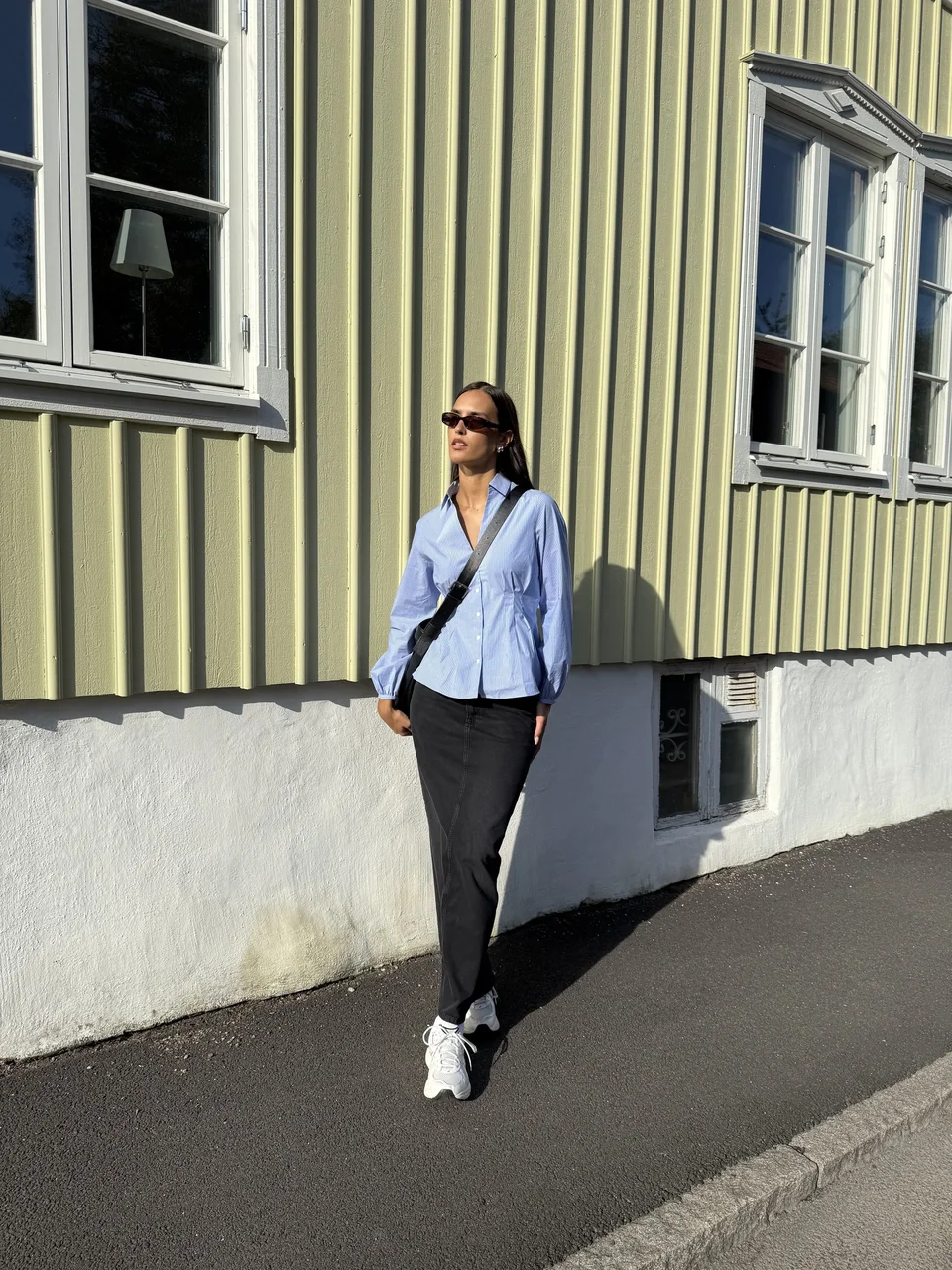 Creator wearing a blue striped shirt beside a wooden building