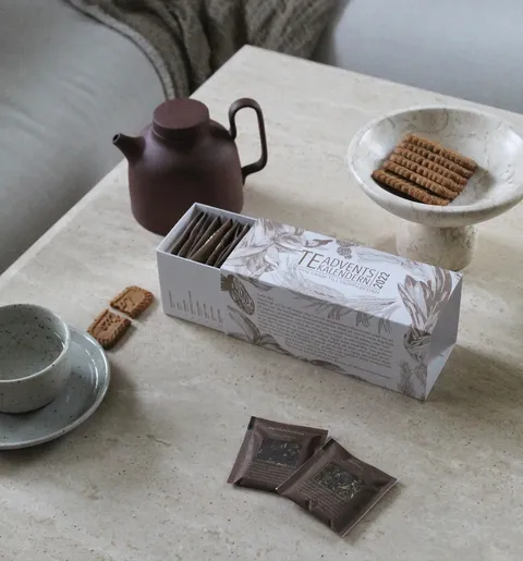 Tea advent calendar, teapot and biscuits on a coffee table
