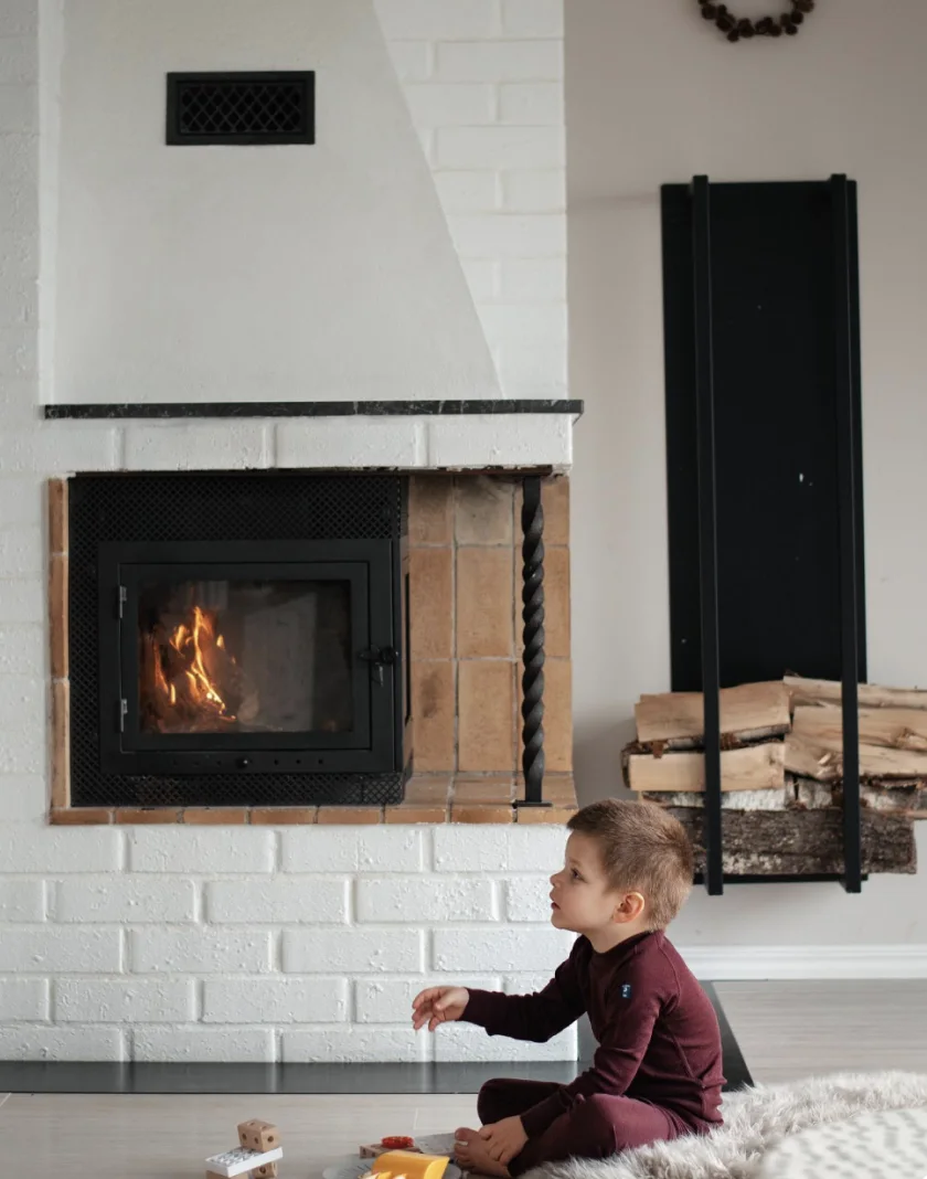 Child playing with toys beside a fireplace