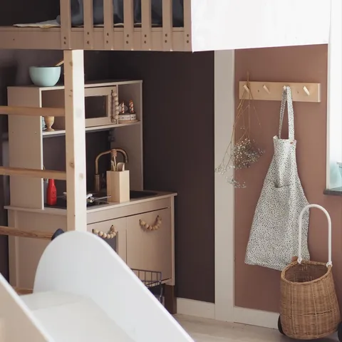 Wooden play kitchen and apron in a child’s room