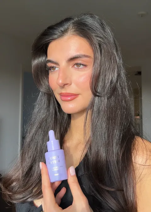 Creator holding Guney & Stem hair oil in natural light
