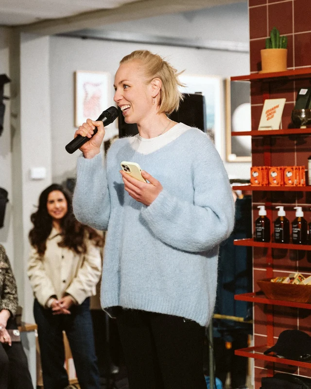 A speaker holding a microphone and notes at Grandpa Store.