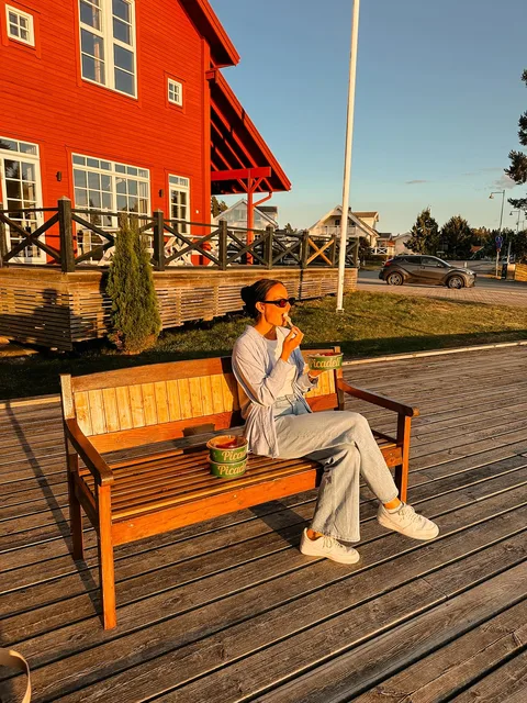 A creator eating a Picadeli salad on a wooden bench in the evening sun