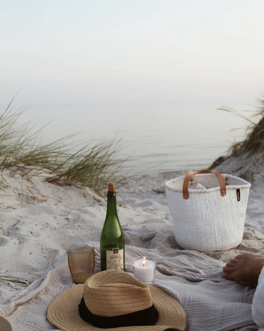 Drinks and a picnic basket on a blanket by the sea