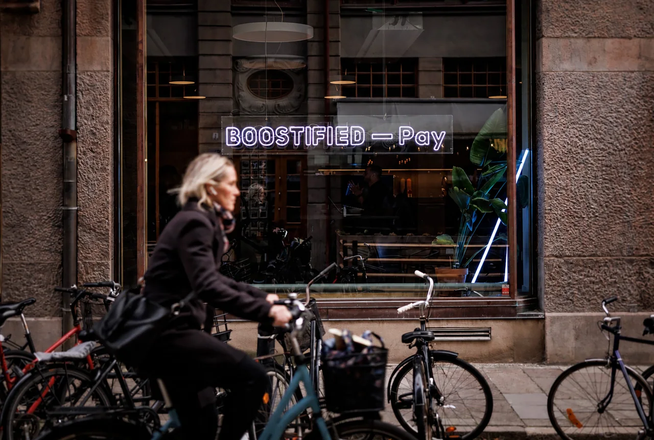 BOOSTIFIED—Pay skiltet i et butiksvindue, med cykler udenfor.