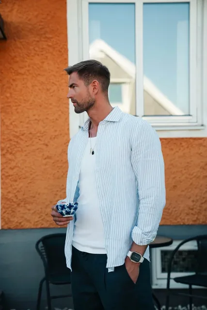 Creator wearing a striped shirt and holding a cup