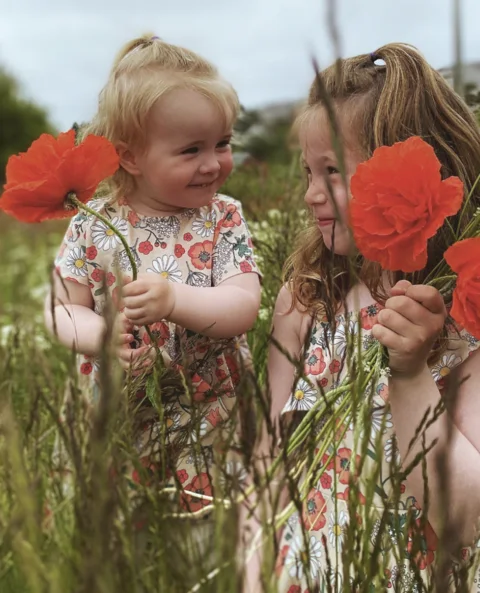 Two children holding flowers outdoors