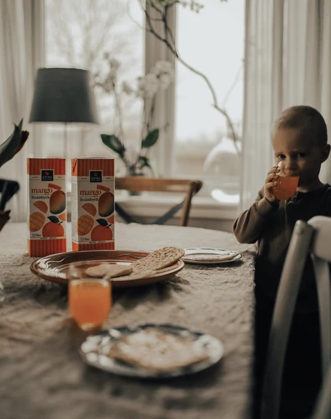 Child enjoying a drink at a breakfast table with Kiviks mango drinks