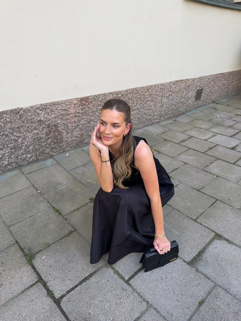 Creator wearing a black dress and sitting on pavement